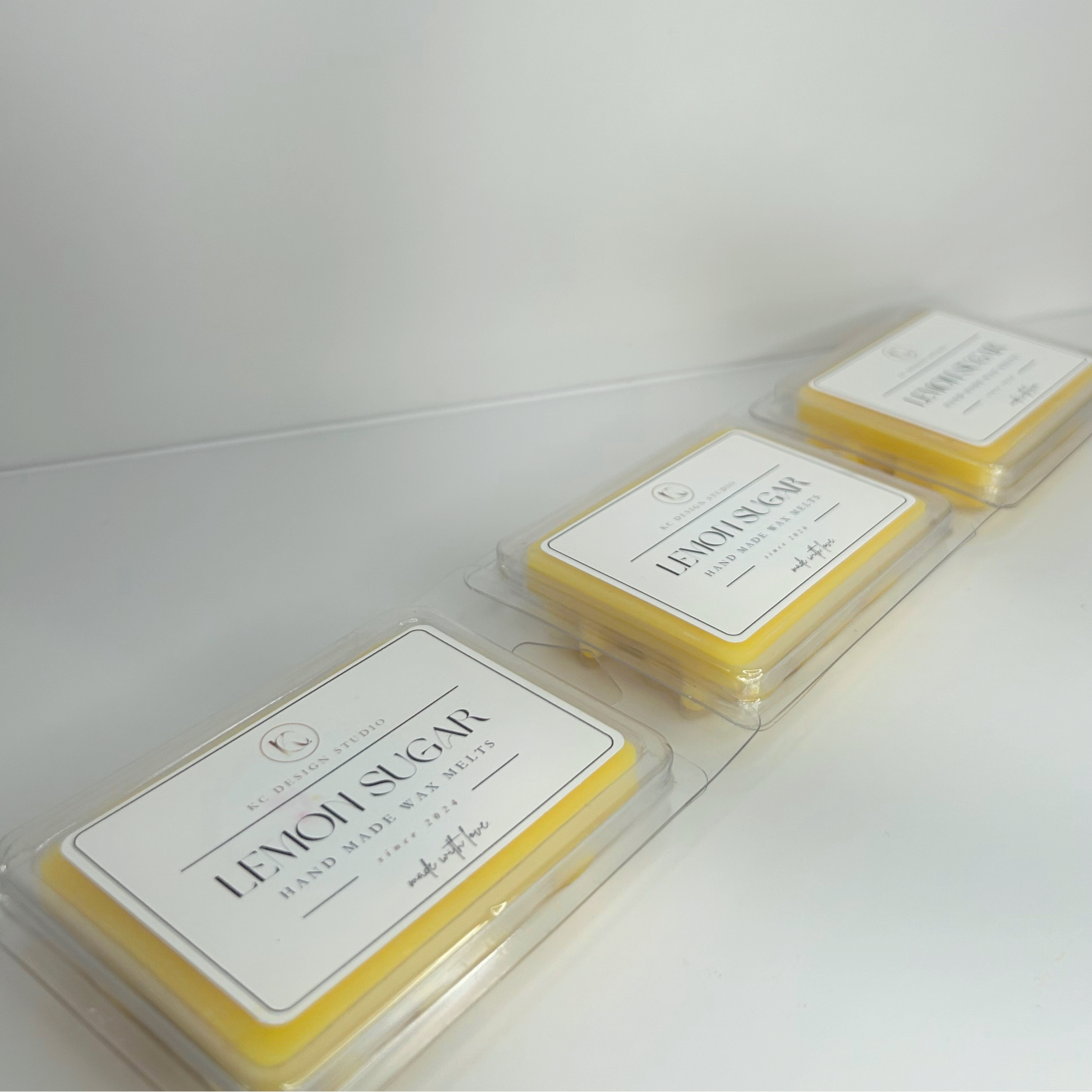 Three Lemon Sugar Cookie wax melt packages lined up, showcasing their vibrant yellow color and labels.