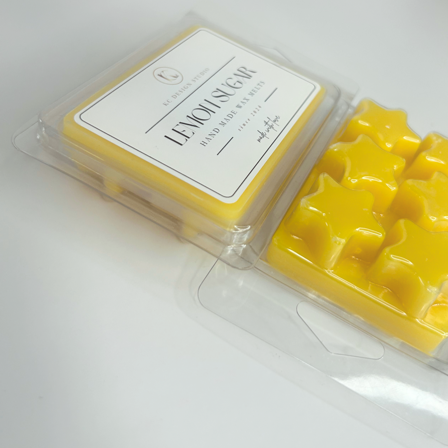 Two Lemon Sugar Cookie wax melt packs lying down, displaying the label and and star shapes.