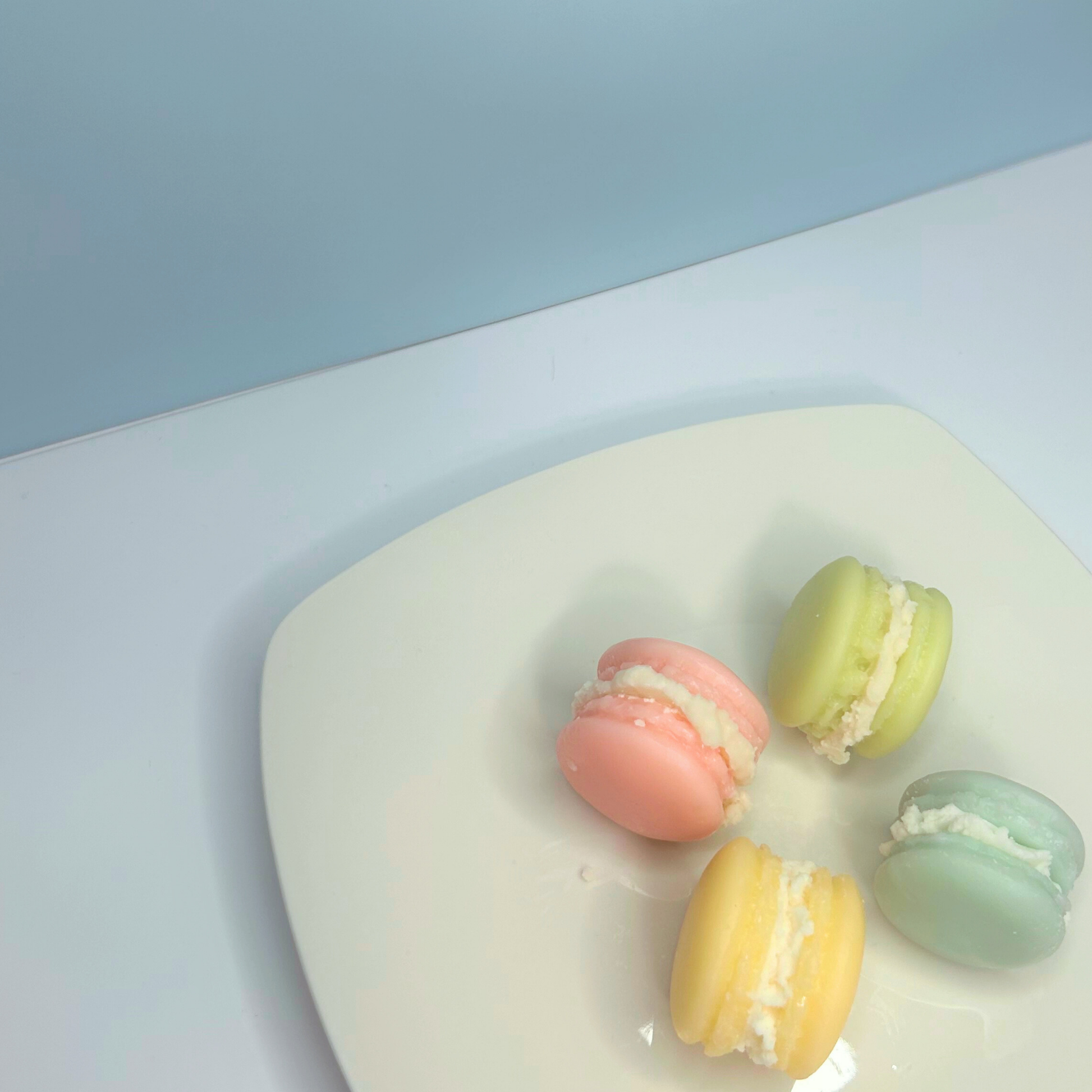 Top view of four Macaroon wax melts resting on a plate, showcasing their delightful colors and sweetness.