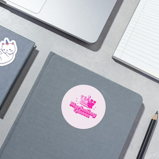 Round Marketing Queen sticker with pink background on a notebook – bold pink crown and marketing icons, perfect for marketing girlies.