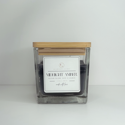 Front view of the 10oz Midnight Amber Candle with the lid on, emphasizing its dark black color and enticing fragrance.