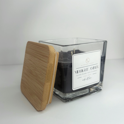 Side view of the 10oz Midnight Amber Candle with the lid resting on the side, highlighting its sophisticated aroma and sleek appearance.