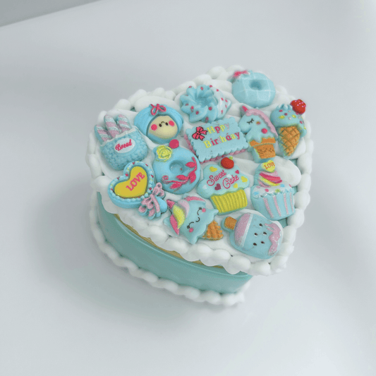 Top view of mini blue kawaii heart-shaped jewelry box adorned with white cream and cute charms.