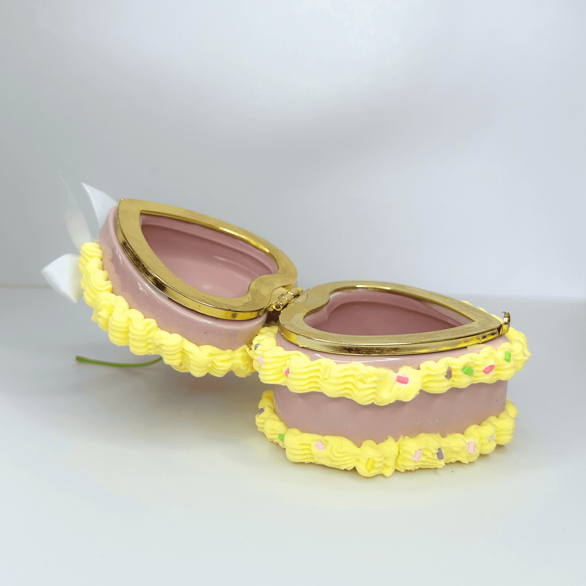 Open side view of a heart-shaped yellow jewelry box decorated as a cake, displaying its interior and whimsical design.