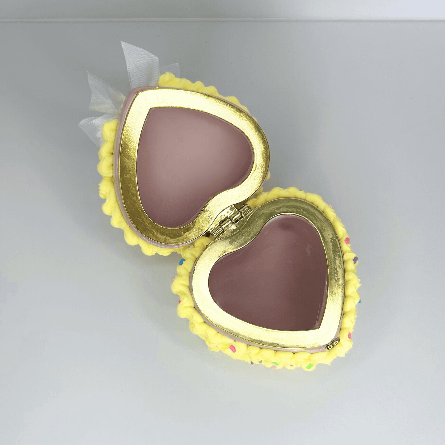 Open top view of a yellow mini jewelry box decorated as a cake, revealing its spacious interior and charming design with sprinkles.