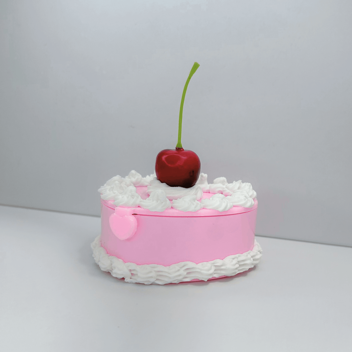 Side View of Cute Pink Mini Cake Jewelry Box with Cream Swirls and Cherry Accent