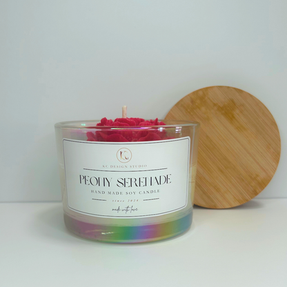 Front view of red Peony Serenade Candle with soft floral notes and lid resting on the wall.