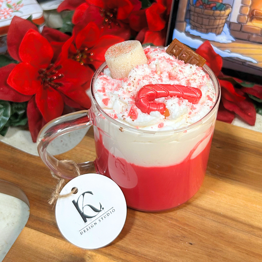 Close-up of peppermint cocoa candle details with textured marshmallow whip, chocolate pieces, marshmallows, and crushed red crumbs.