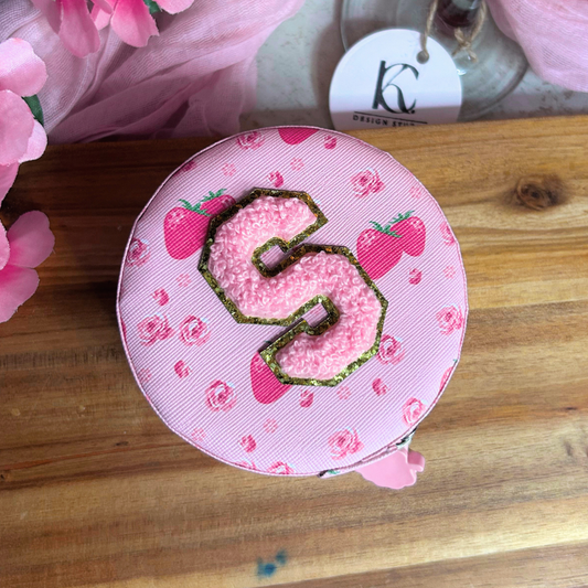 Top view of a pink personalized Valentine’s jewelry travel case with initial on top displayed on a cozy Valentine’s background