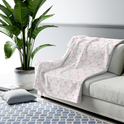 White sofa with a pink patterned throw blanket in a living room setting.