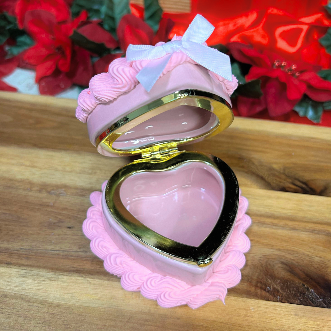 Pink heart-shaped jewelry box on a wooden surface with floral background