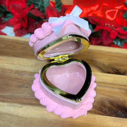 Pink heart-shaped jewelry box on a wooden surface with floral background