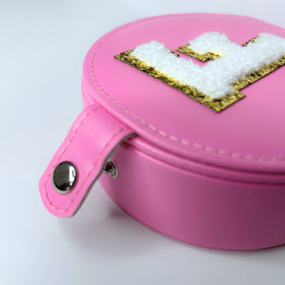 Close-up of button closure on pink jewelry travel case with initial.