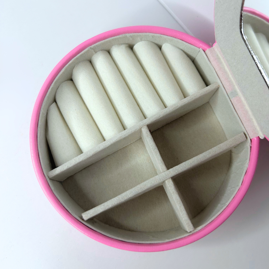 Detailed close-up of inside pink jewelry case with small mirror and sections.