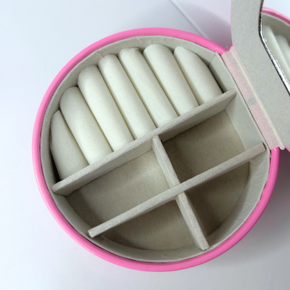Detailed close-up of inside pink jewelry case with small mirror and sections.