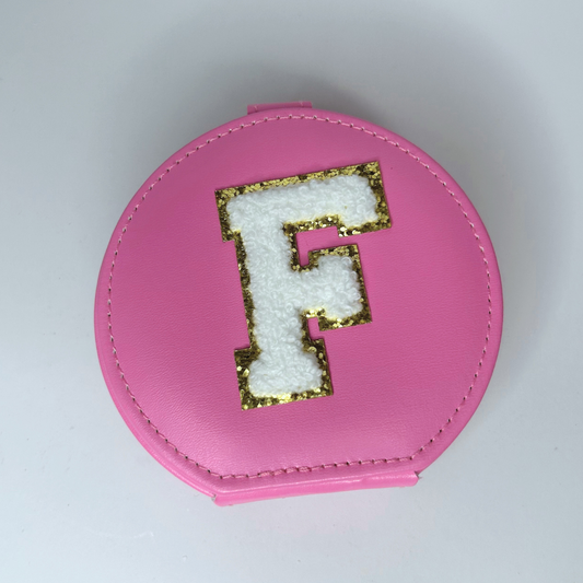 Top view of pink personalized round jewelry travel case with letter initial.