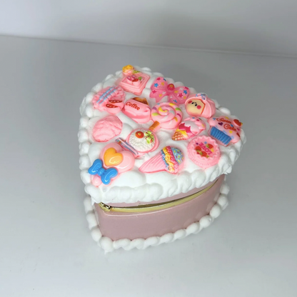 Close-up of a pink kawaii mini heart-shaped jewelry box with curvy cream and adorable charms.