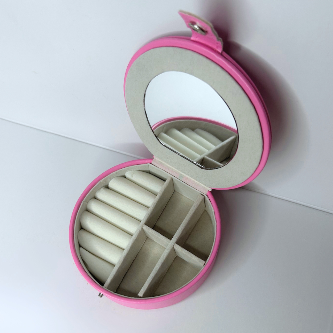 Open top view of pink jewelry case showing mirror and divided compartments.
