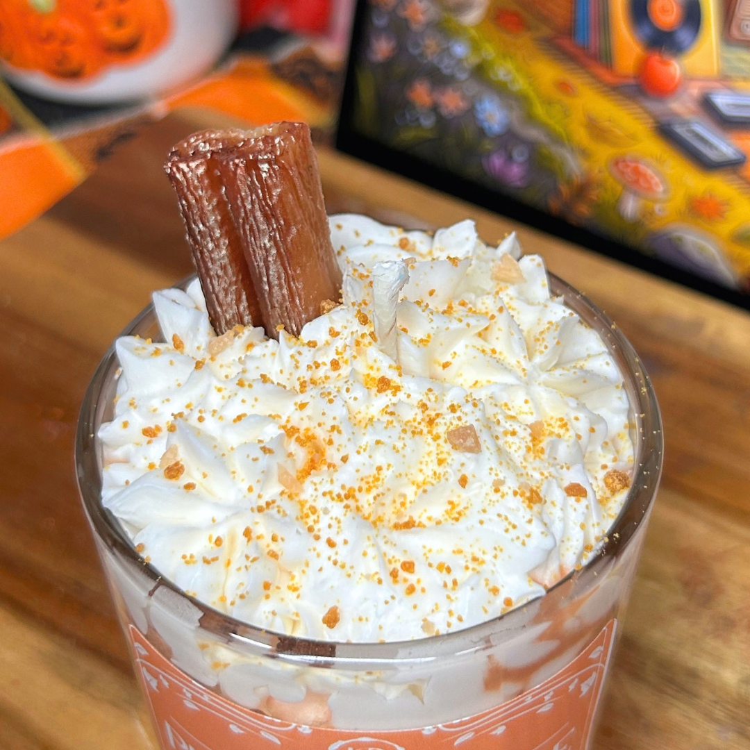 Top view of the Pumpkin Spice Latte candle showing the white whipped wax, brown crumbs, and cinnamon stick topping.