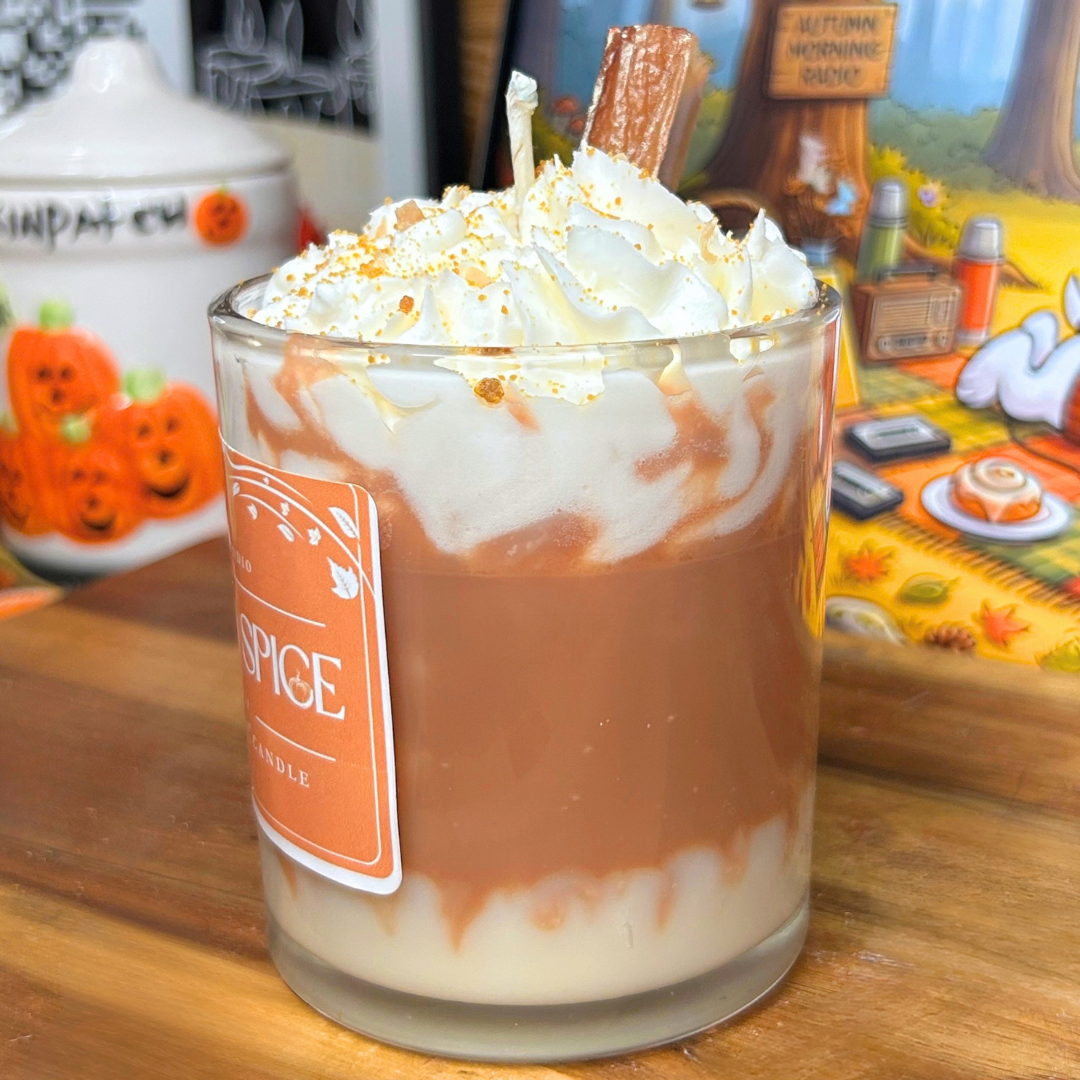 Side view of the Pumpkin Spice Latte candle showing the white and brown layered base, whipped wax topping, brown crumbs, and cinnamon stick.
