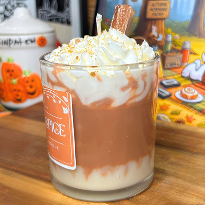 Side view of the Pumpkin Spice Latte candle showing the white and brown layered base, whipped wax topping, brown crumbs, and cinnamon stick.