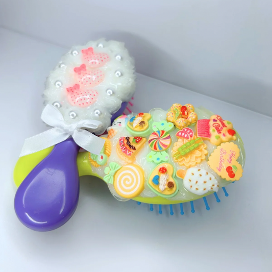 Side-by-side shot of the purple and yellow travel hair brushes with soft silicone bristles and cute charms, the ultimate duo for styling on the go