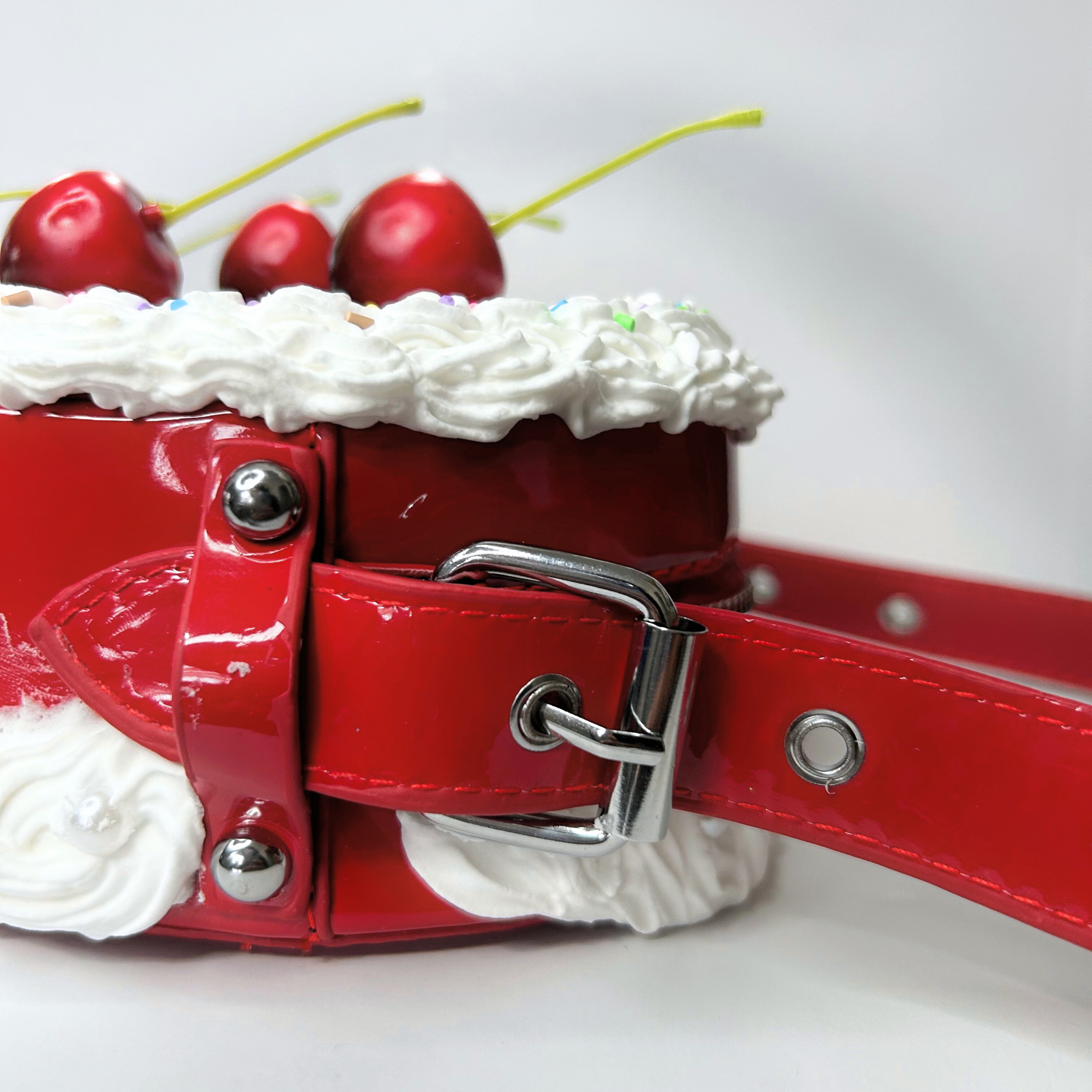 Close-up of a red heart-shaped cake purse showing the textured frosting detail and cherry decoration.