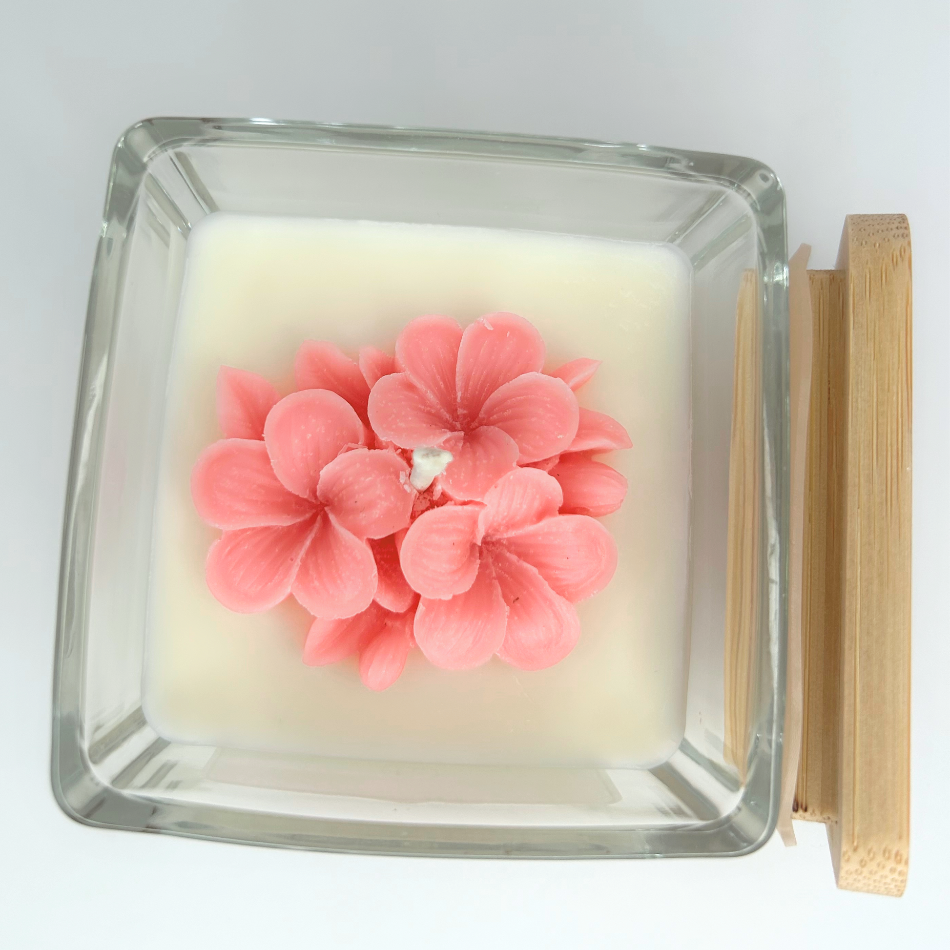 Top view of Sakura Aura Candle with lid resting on side, featuring a close-up of the soft pink flowers and candle's surface.