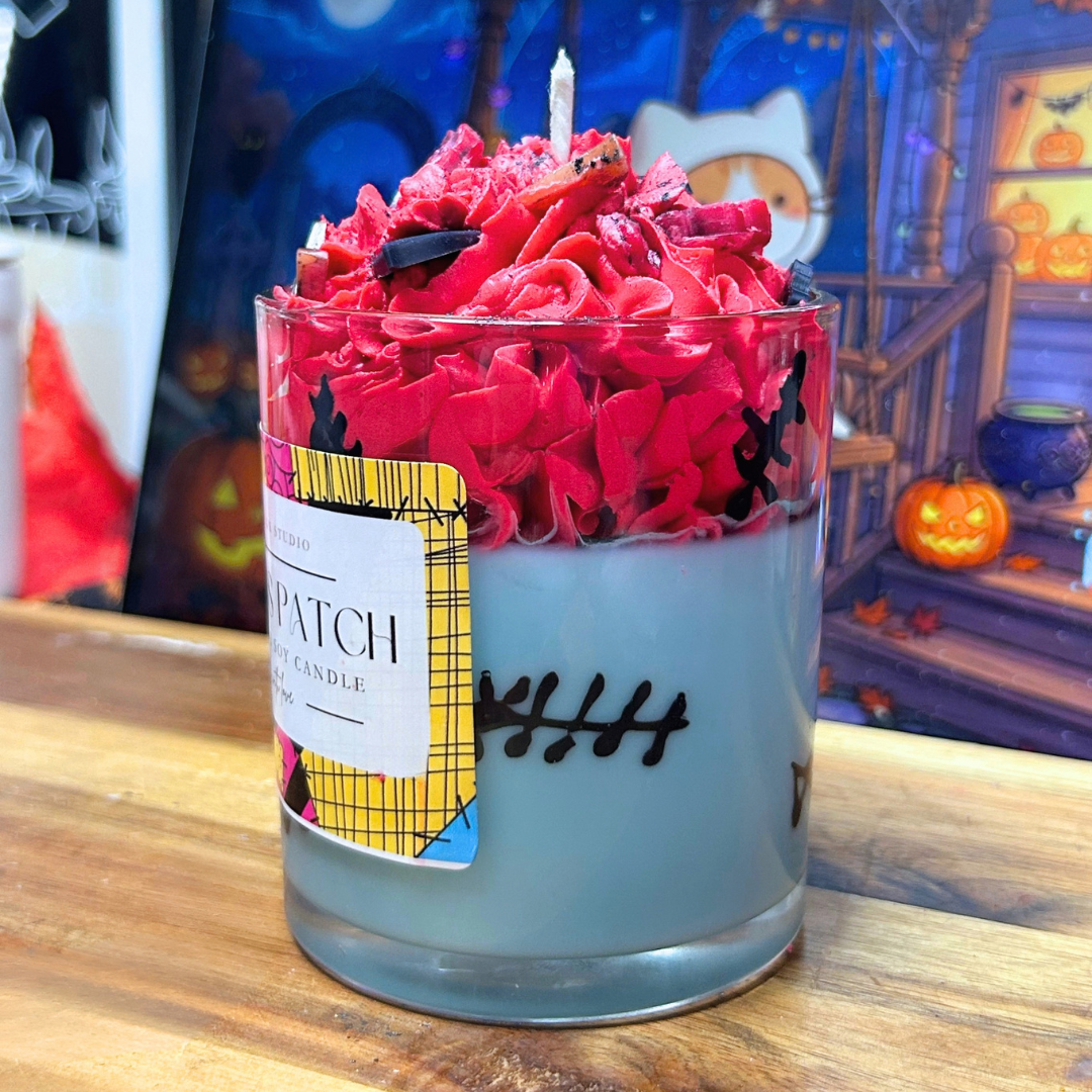 Side view of Sally’s Patch Candle highlighting the hand-drawn wax stitches around the light blue glass and the red whipped wax topping.