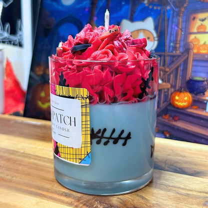 Side view of Sally’s Patch Candle highlighting the hand-drawn wax stitches around the light blue glass and the red whipped wax topping.