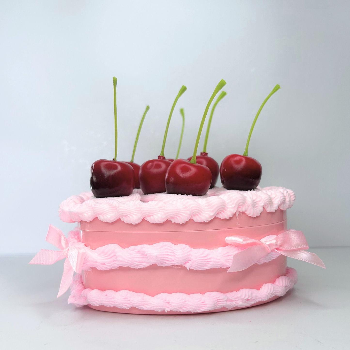 Side view of the pink jewelry box decorated with cherries, pearls, and pink mini bows, highlighting its elegant shape and intricate detailing.