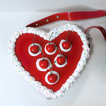 Heart-shaped cake with red cherries and white frosting on a white background