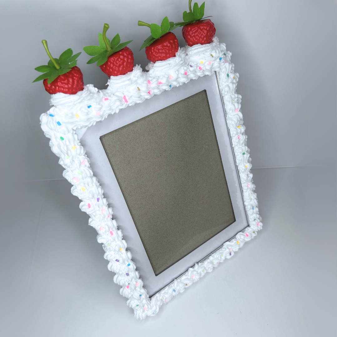 Full view of strawberry cake picture frame with white frosting, sprinkles, and strawberries on top.