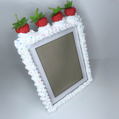 Full view of strawberry cake picture frame with white frosting, sprinkles, and strawberries on top.