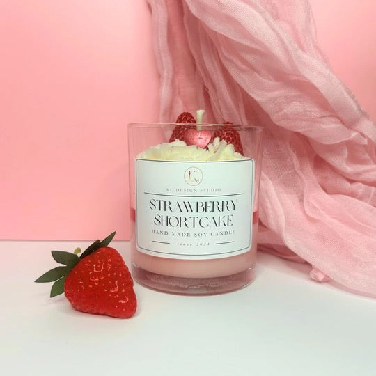 Front view of Strawberry Shortcake Candle with layers of strawberry, caramel crumbs, and vanilla whipped cream, topped with two strawberries and a mini heart.