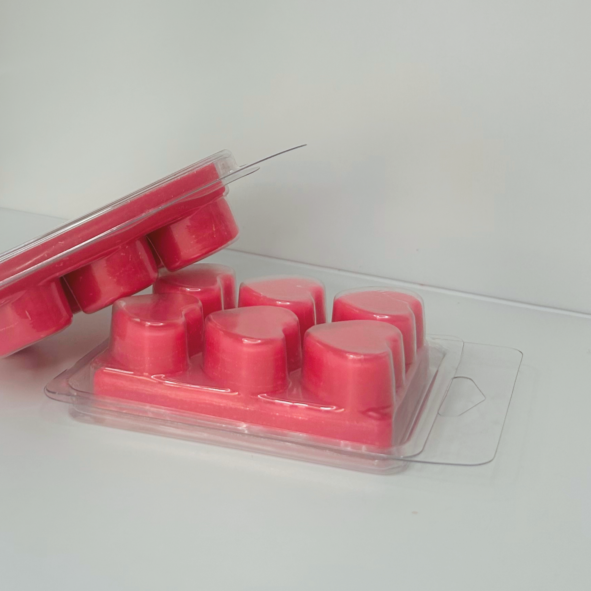 Side view of stacked packs of Strawberry Wax Melts, displaying heart shapes and product label.