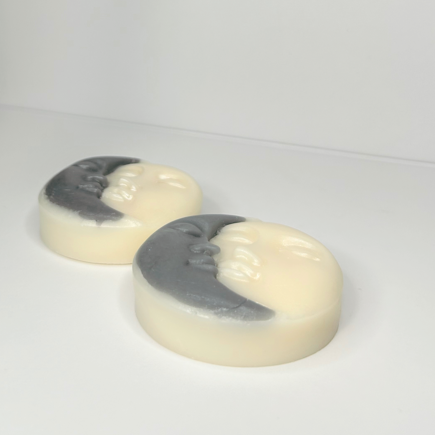  Side view of two Sun & Moon wax melts highlighting their unique shapes, colors, and sleeping faces.