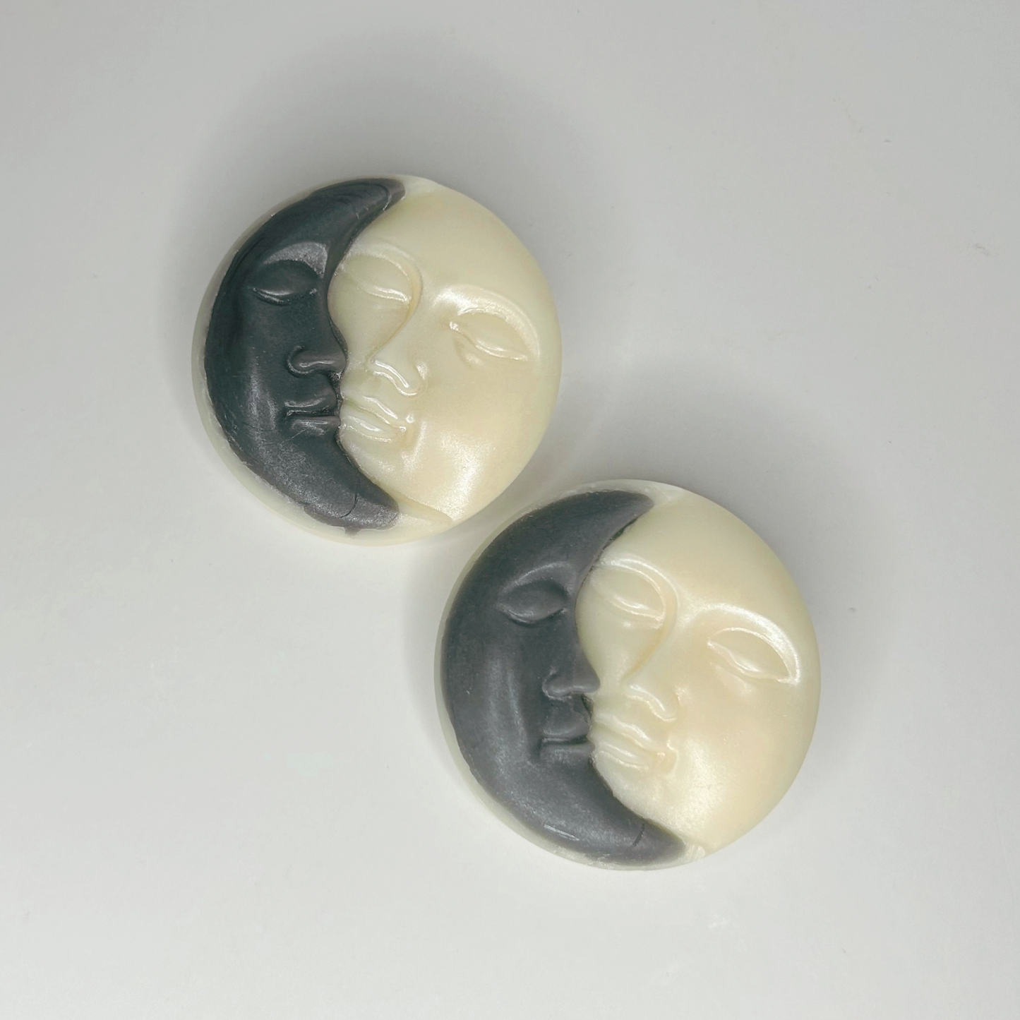 Top view of two Sun & Moon wax melts showcasing their celestial designs and sleeping faces.