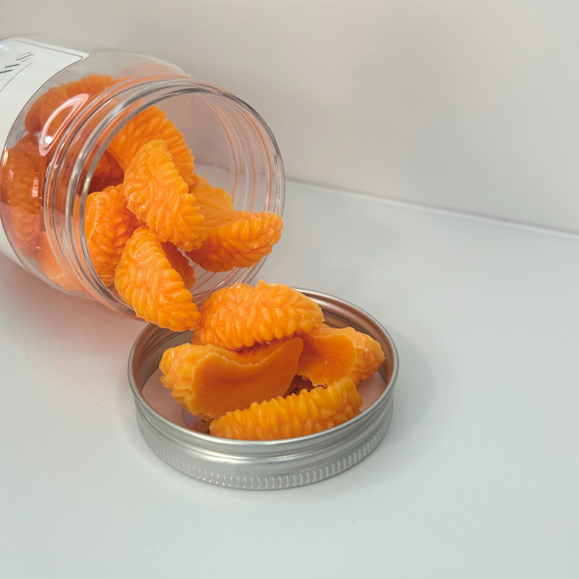 Close-up view of Sweet Mandarin wax melts spilling out of the jar, showcasing their vibrant color and texture.