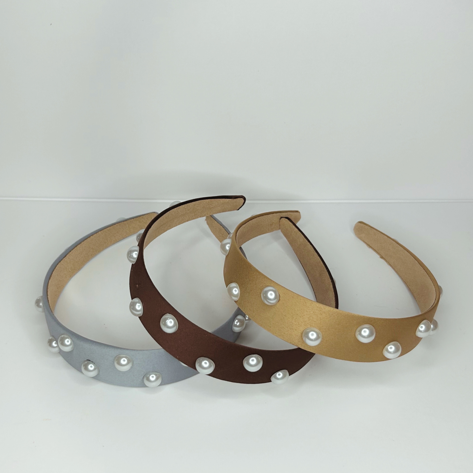 Top view of pearl headbands in baby blue, brown, and gold, highlighting their luxurious design and pearl embellishments.