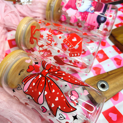 Clear glass bottles with red bow and heart designs on a pink and white heart-patterned background.