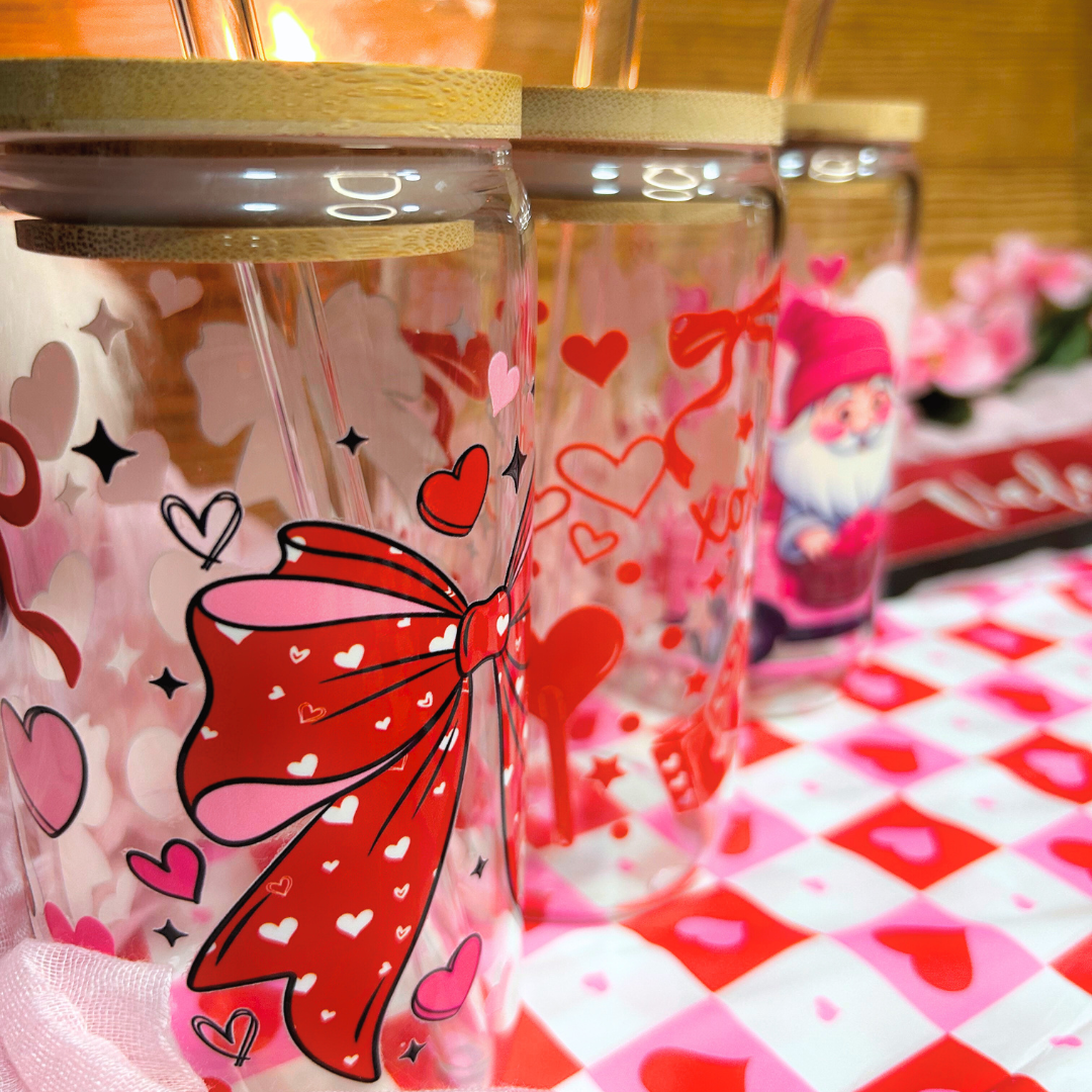 Clear tumbler closeup with red bow and heart designs on a checkered tablecloth.