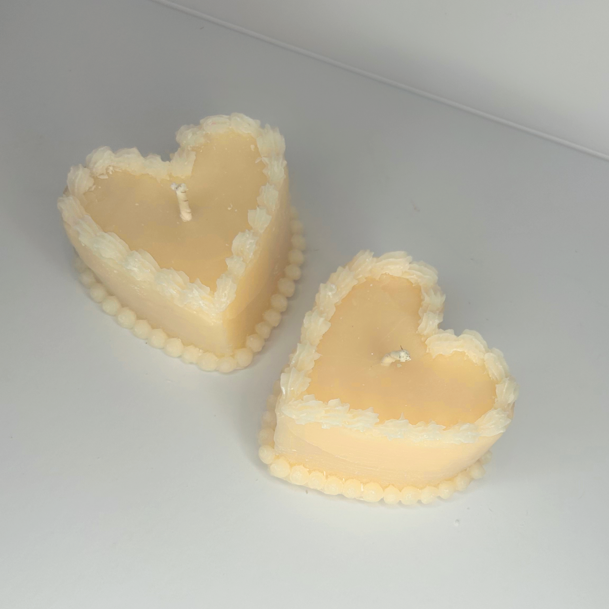 Close-up of two Decorative Vintage Heart-Shaped Cake Candles, emphasizing the textures and colors of the wax and wicks.