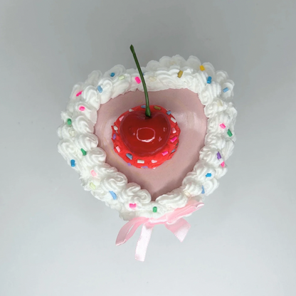 Top view of the white mini cake jewelry box, featuring its heart shape and elegant pink bow.