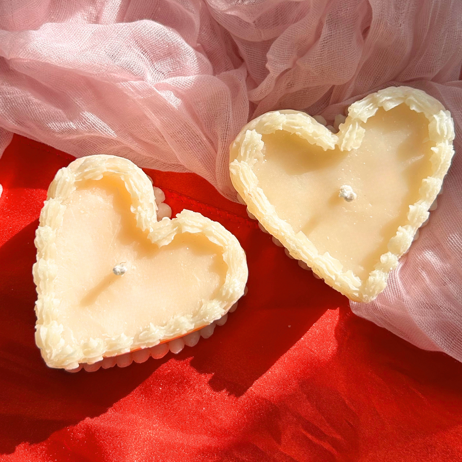 Top view of two white decorative vintage heart-shaped cake candles, featuring intricate frosting-like details for an elegant and timeless design.